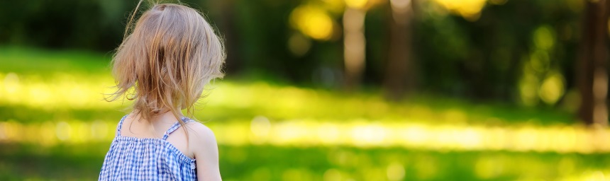A young girl photographed from behind in a garden